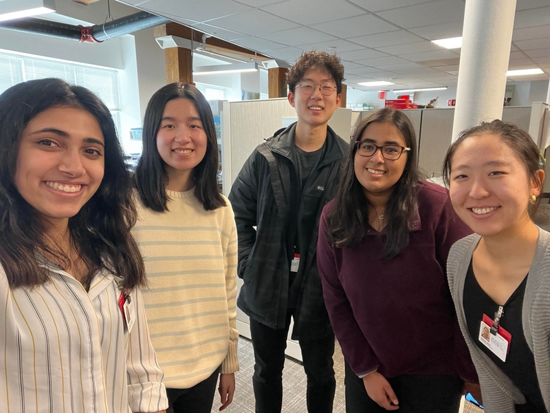 5 people smile and pose together for a photo indoors while wearing Boston Medical Center badges.