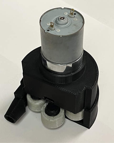 The device has many parts made of 3D-printed black and grey material, and is smaller than a fist. A metal cylindrical motor sits on top.