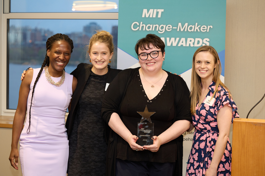 Four women standing together, with one holding an award
