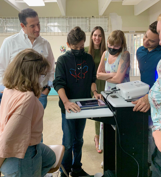 Several people gathered around looking at a student's project on their digital tablet.