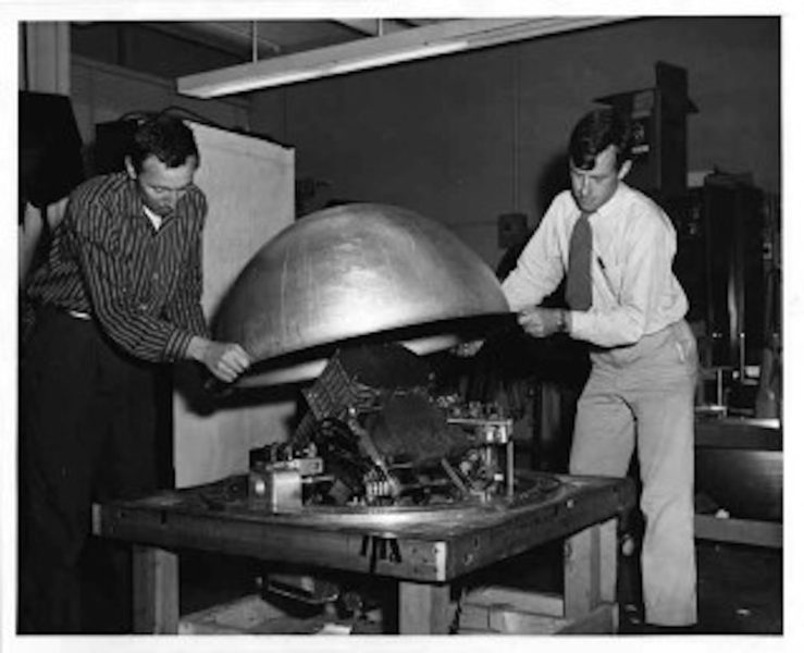 Black-and-white photo from 1956 of two men assembling a balloon gondola.