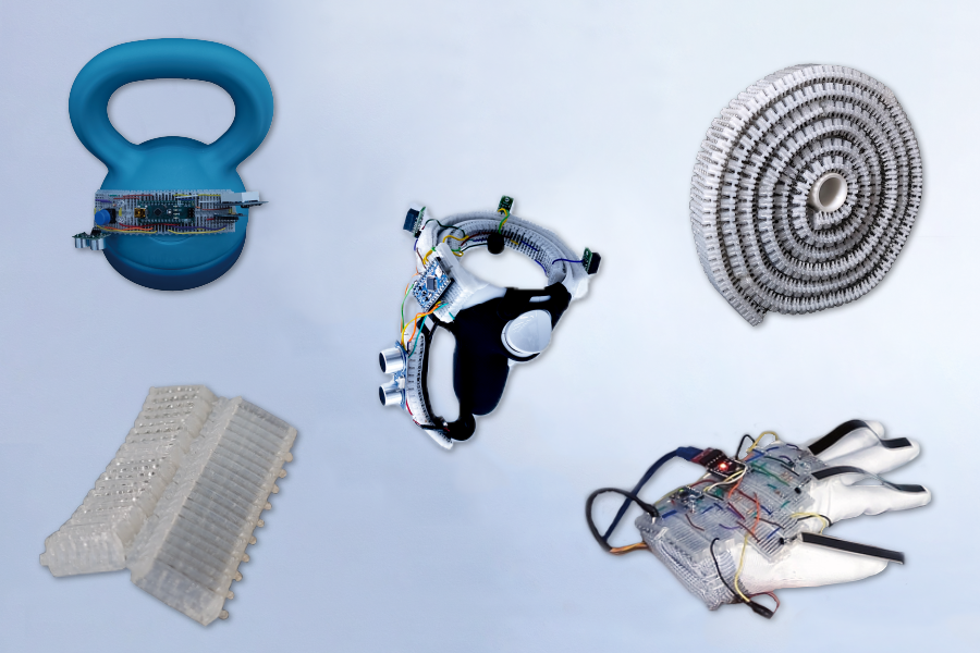 Five objects appear on a whitish background: A blue kettlebell with some microchip components, a silver ringlike object with wires, a roll of corrugated white plastic, a white glove with wires on it, and an off-white corrugated piece of plastic. 