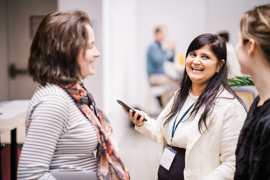Photo of three business women in conversation. The woman in the middle is laughing.
