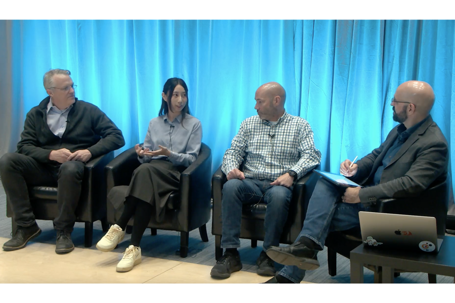 Four MIT professors are seated in front of a blue curtain during their panel discussion.