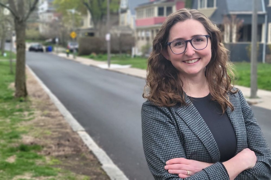 Portrait of Nicole Wilson, standing on a quiet street with wooden houses