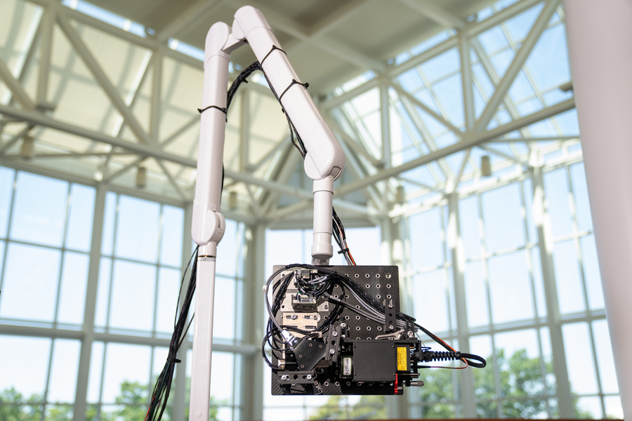 A laser and optical setup is attached to a moveable robotic arm