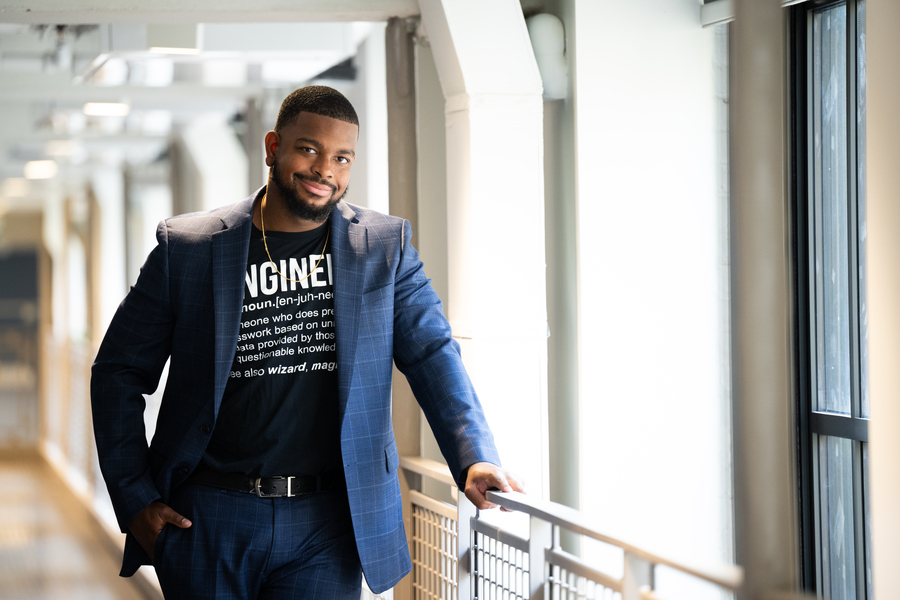 Michael West, in a blazer and T-shirt, stands next to window in hallway.
