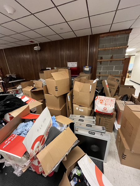 Assorted cardboard boxes, mostly open, piled haphazardly in a storage area