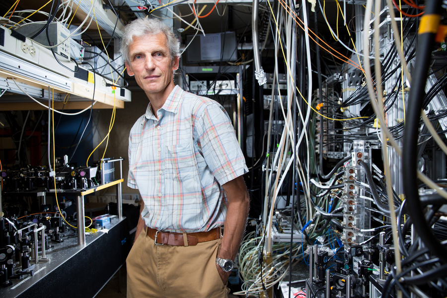 Wolfgang Ketterle stands in a laboratory filled with many wires and electronics
