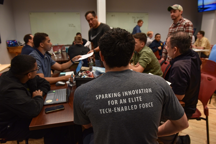 A group of SOCOM Ignite students gather around a classroom table in discussion.