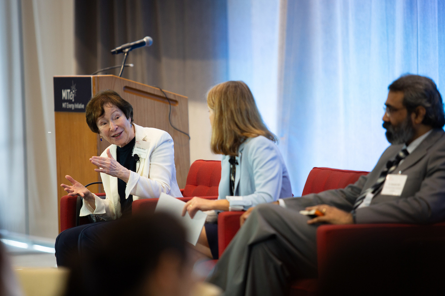 Leaning forward and gesturing, Suzanne Berger speaks from her seat on stage with other panelists. 