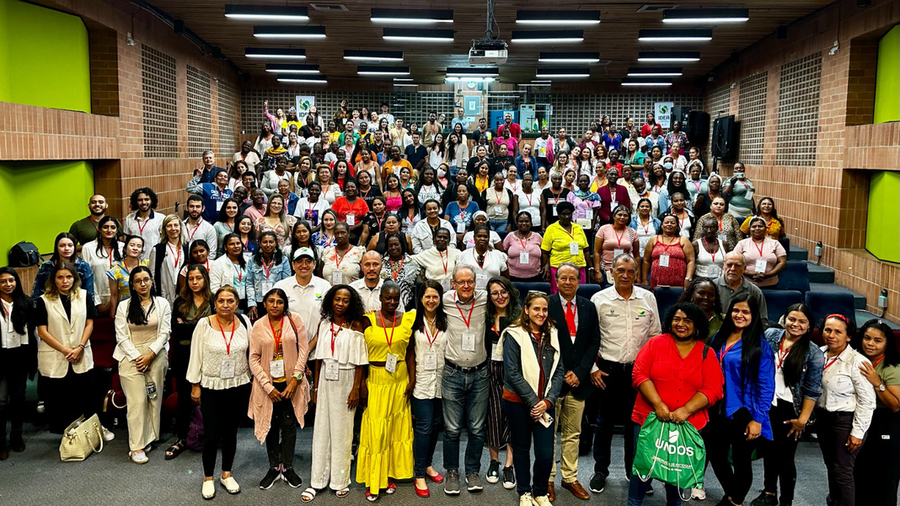 Hundreds of participants of the national conference of women artisanal miners stand for a photo in an auditorium