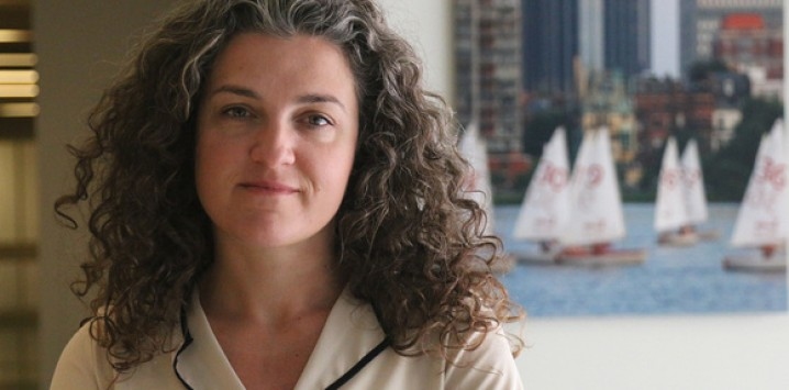 Lerna Ekmekciouglu in front of a window with sailboats on the Charles River in the background. 