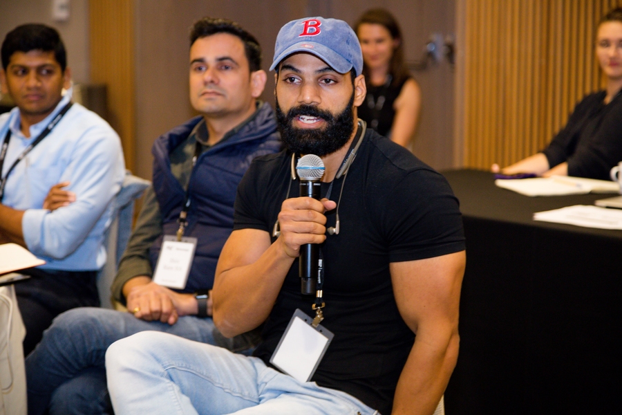 Jitendra Chouksey, seated and speaking into a microphone in a room with several others looking on