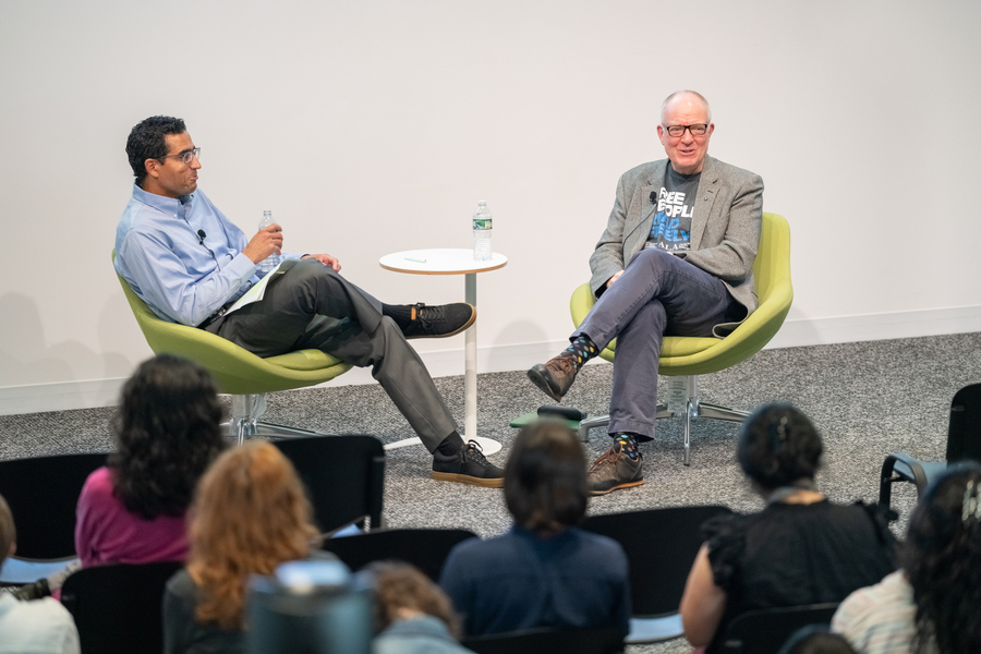 Malick Ghachem and Richard Ovenden sit in bucket chairs in front of an audience.