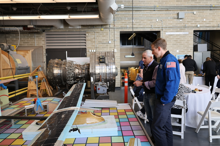 Woody Hoburg and a colleague look down at a course 16 project, which appears to be a solar-powered aircraft, inside a lab space