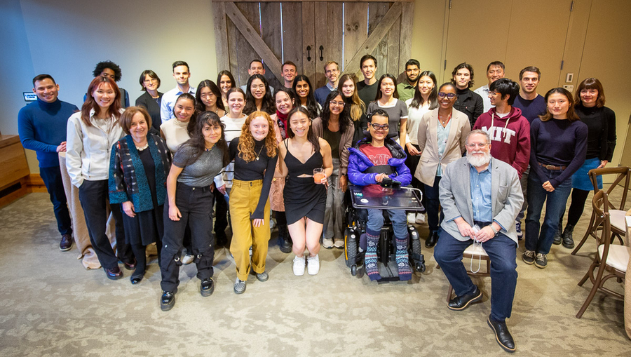 More than 30 people pose for a group photo in front of a sliding screen cover at Catalyst restaurant