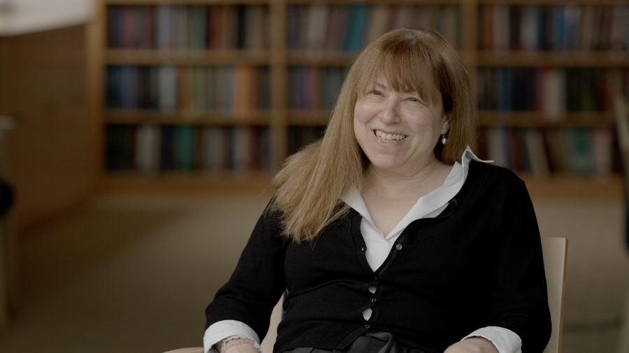 Elly Nedivi smiles as she sits in a chair in a library