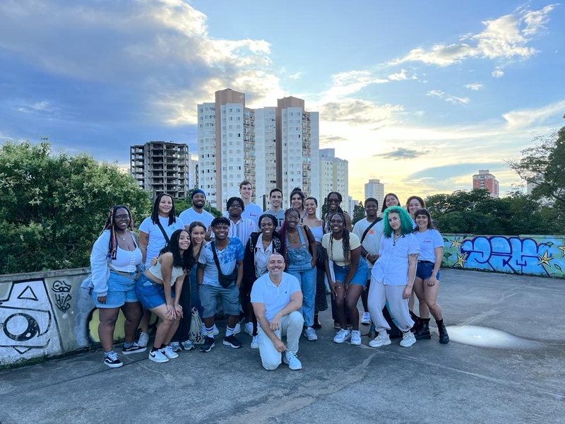 20 people pose on a rooftop with high-rise buildings in the background
