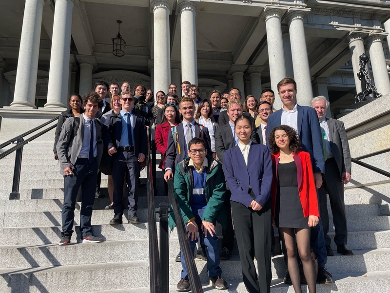About 30 people, including 26 MIT students, pose on the steps of the Eisenhower Executive Office Building.