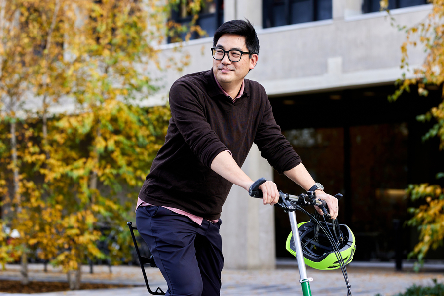 David Hsu rides a bike, which is half-seen, while outside.