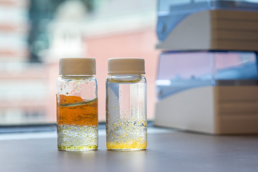 Close-up of two small jars of water with small beads of orange and yellow