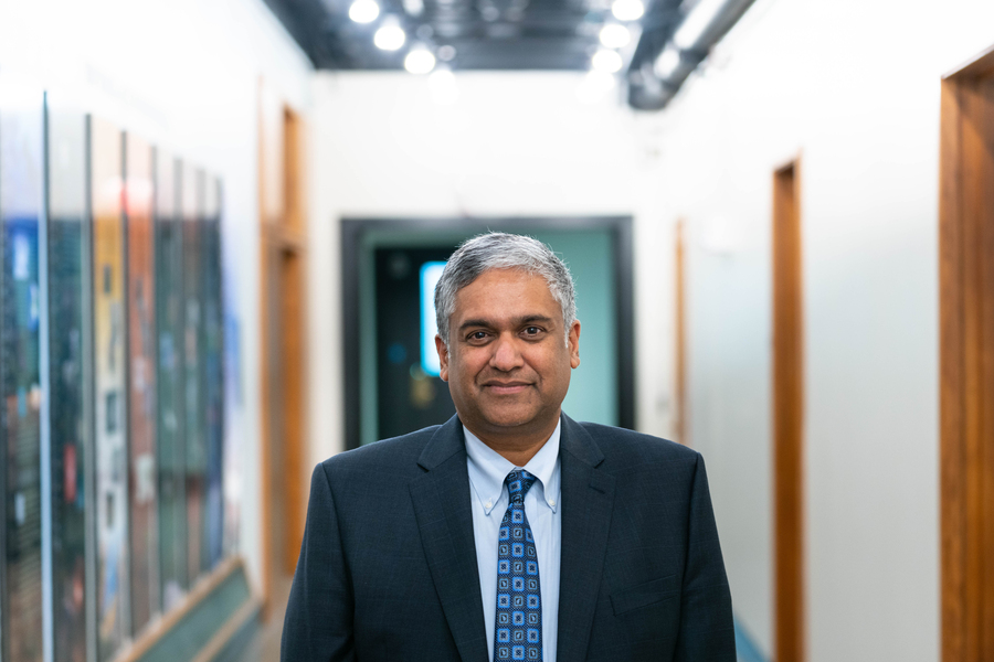 Anantha Chandrahasan stands inside of blurred lit hallway.
