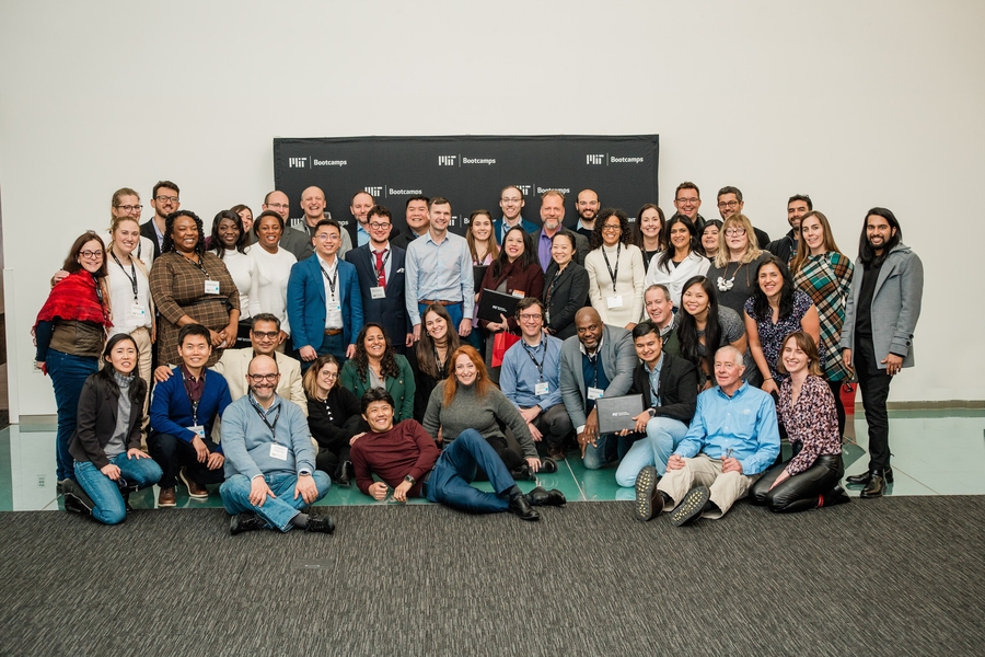 Indoor group photo of approximately 50 people posing together against a white wall