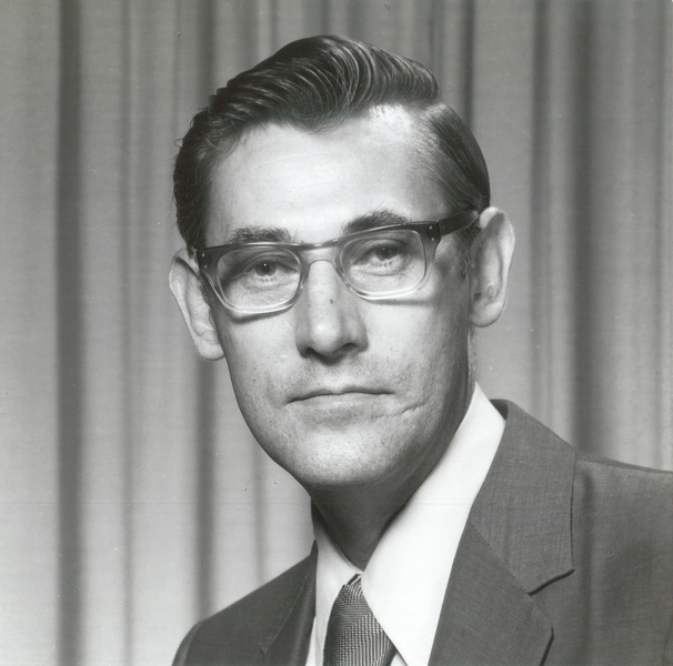 Black and white 1950s-era portrait of David Lanning wearing a suit and tie against a curtained background