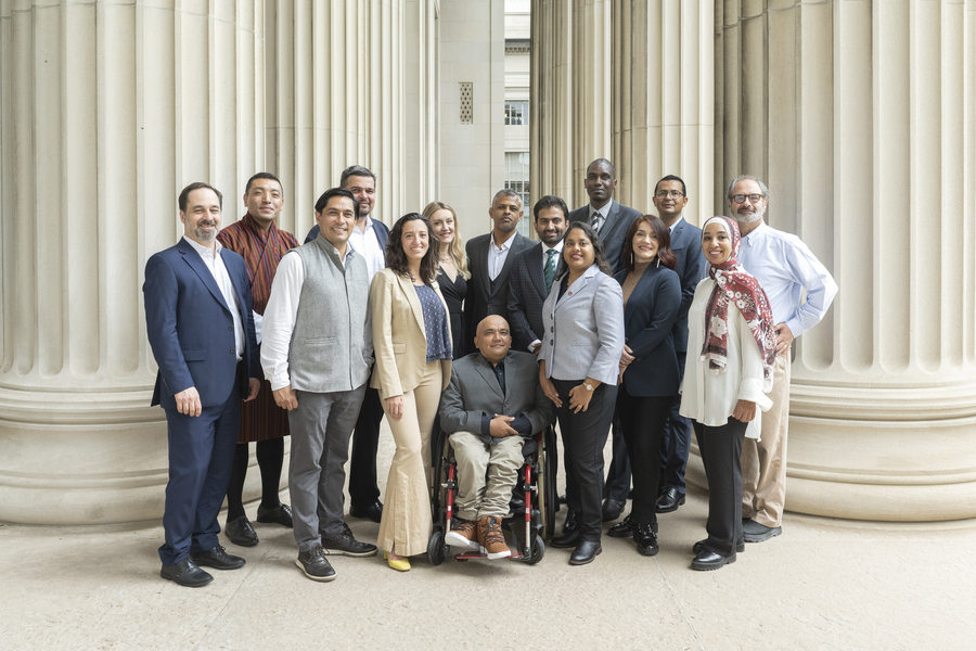 16 people pose between rows of large columns
