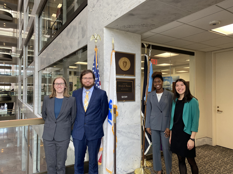 Four CVD participants in business attire pose in front of Senator Elizabeth Warren’s office.