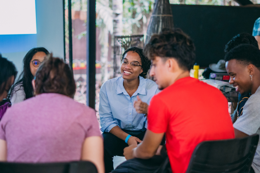 A group of people chat and smile in a circle.