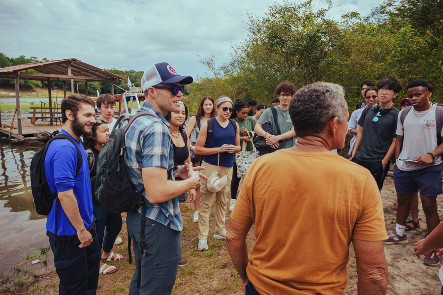 A group of people outside in nature near a river.
