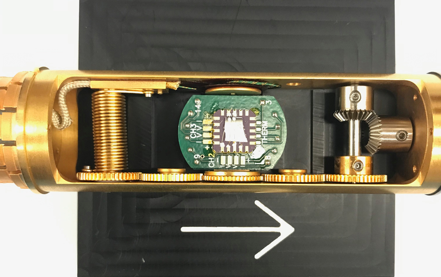 The gold cylindrical device has a circuit board and gears inside. 