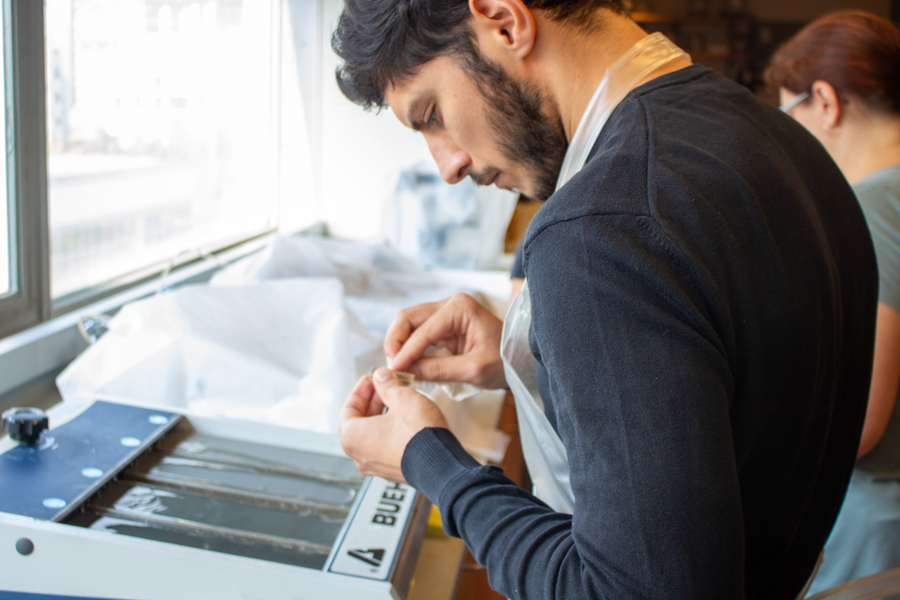 A student uses fine sandpaper to grind a small sample held between his thumb and forefinger