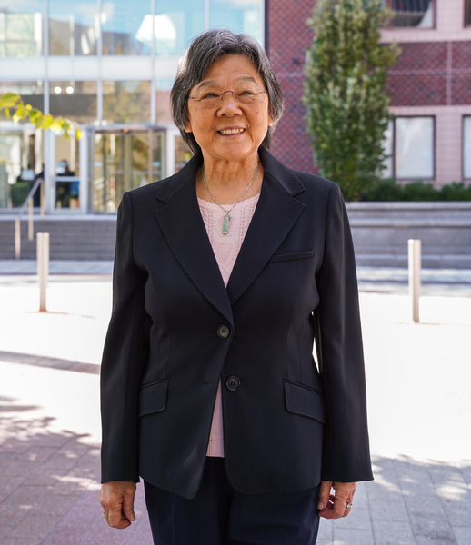 Jane-Jane Chen poses in front of a brick and glass building