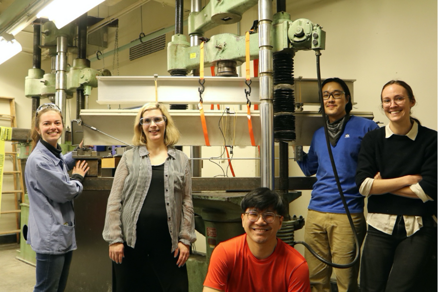 Five researchers smile next to a prototype of cement blocks in the lab.