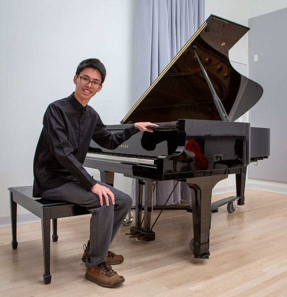MIT senior Holden Mui sits at a piano