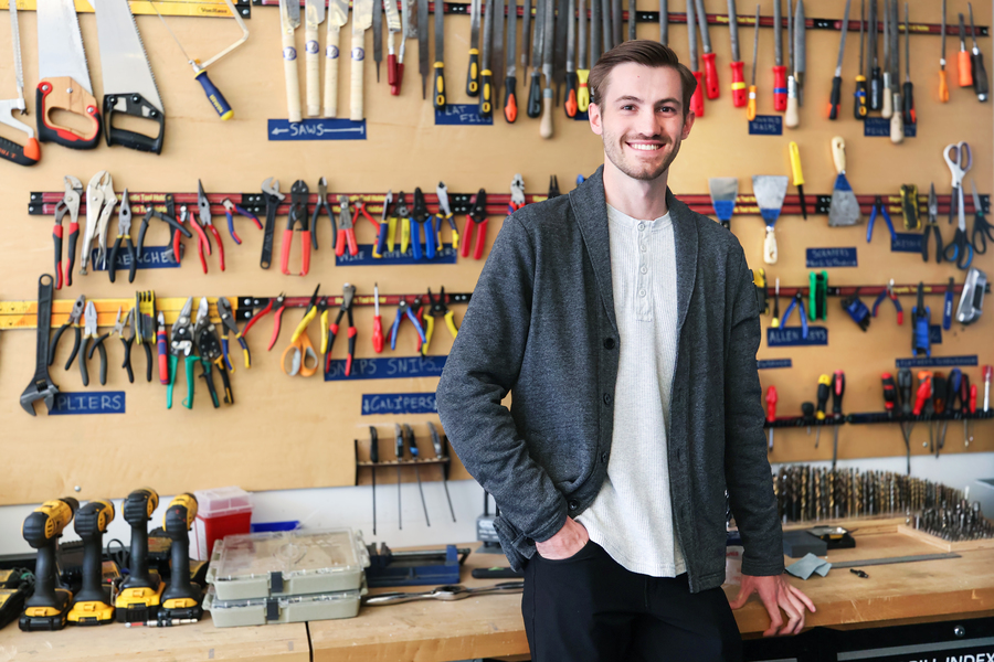 Zane Schemmer stands in front of a workbench.
