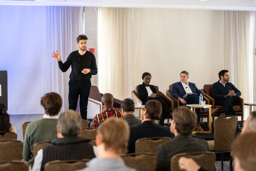 Ely Sandler stands in front of fellow panelists and speaks to an audience