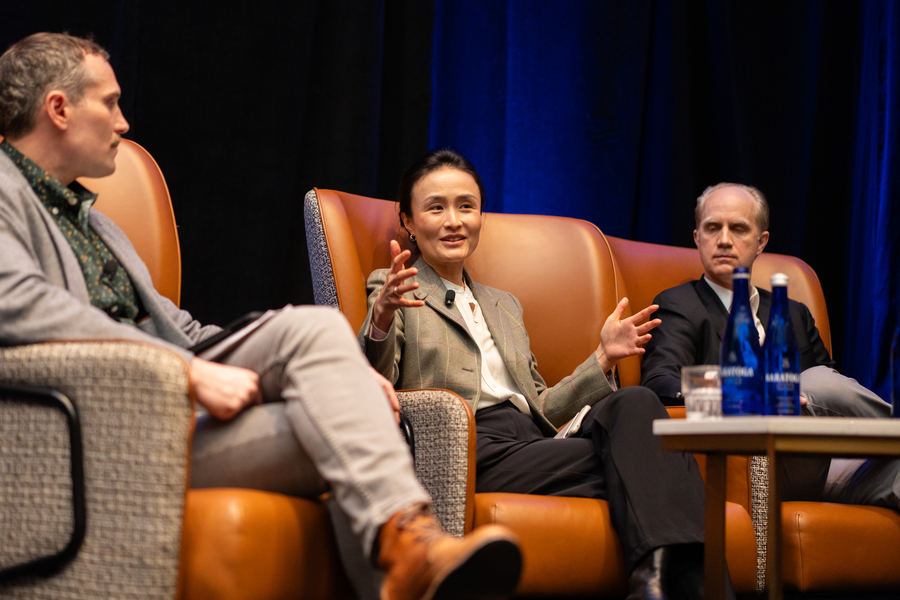Lucia Tian sits between two others on a stage and is speaking.