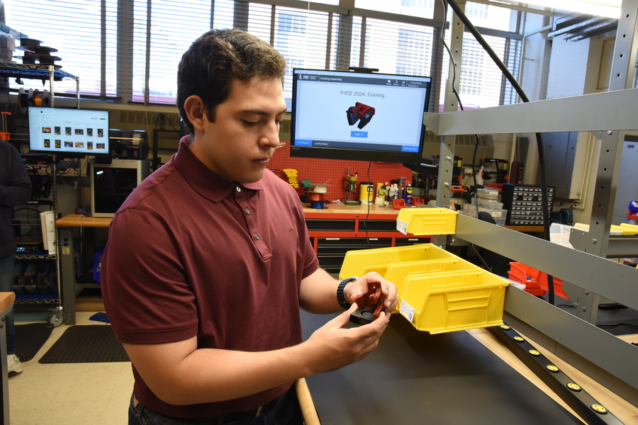 Ángel Mario Alarcón López holds a fiber extrusion device in an MIT lab.