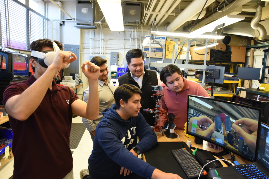 In a lab, Gilberto Ramírez Tamez wears a VR headset, while four others look at a computer screen mimicking what Tamez sees 