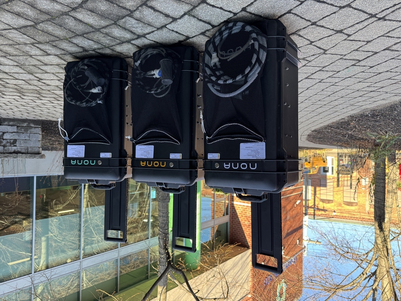 3 suitcase-like desalination devices on a cobblestone patio outside a building