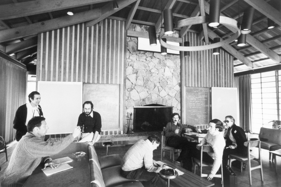 1975 photo showing seven attendees chatting in a lodge.