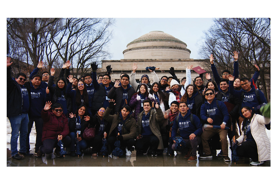 About 50 individuals, most wearing BREIT sweatshirts, wave in a group photo with the MIT Dome behind them