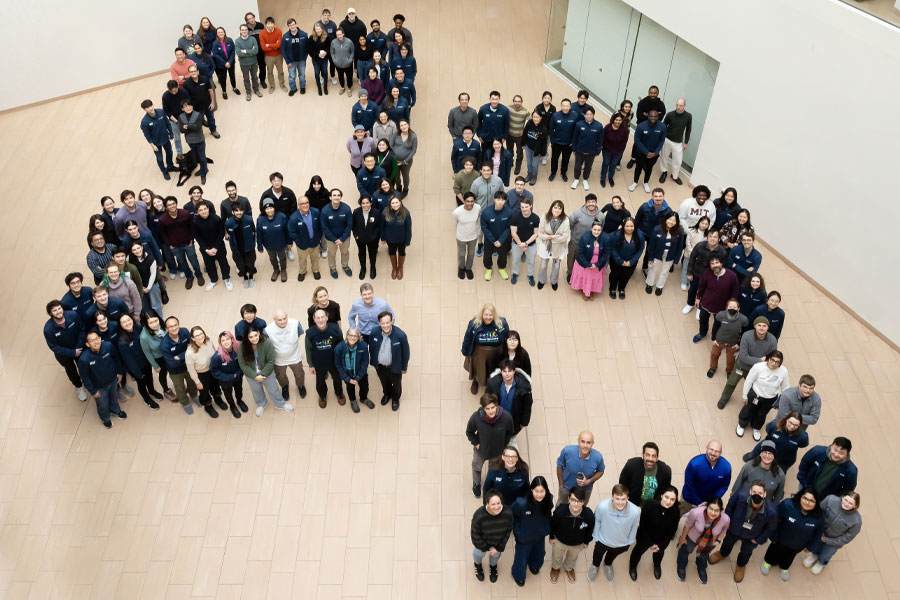 A large group of people standing in the shape of the number 25. 