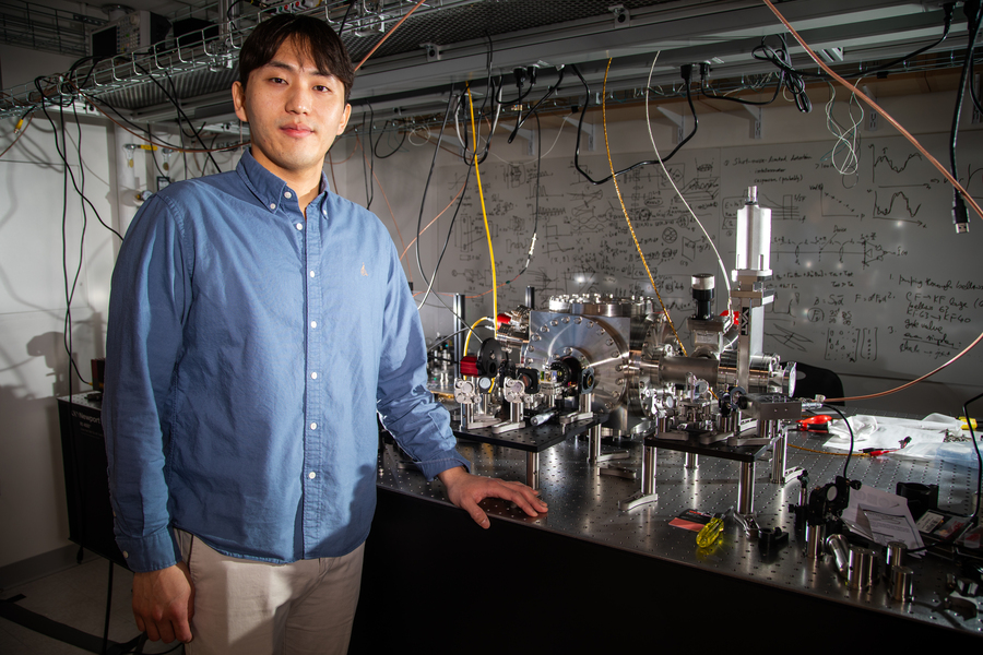 Dongchel Shin stands next to a tabletop experimental setup 