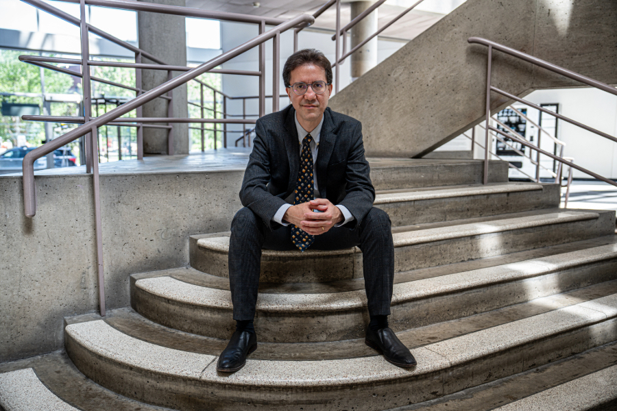 A man in a suit and tie sits on stone steps in a building atrium