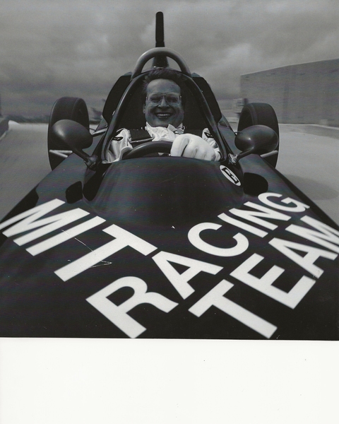 Grayscale photo of Kent Bowen driving a racing car, taken from the vehicle’s hood.